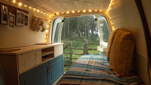 Charming van interior with string lights and forest view, perfect for camping enthusiasts.