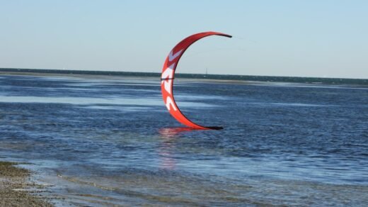 a red and white sail sitting on top of a body of water