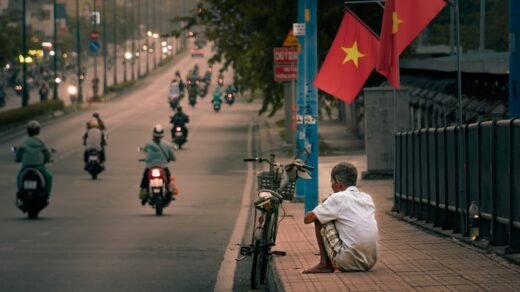 a man sitting on the side of a road next to a motorcycle