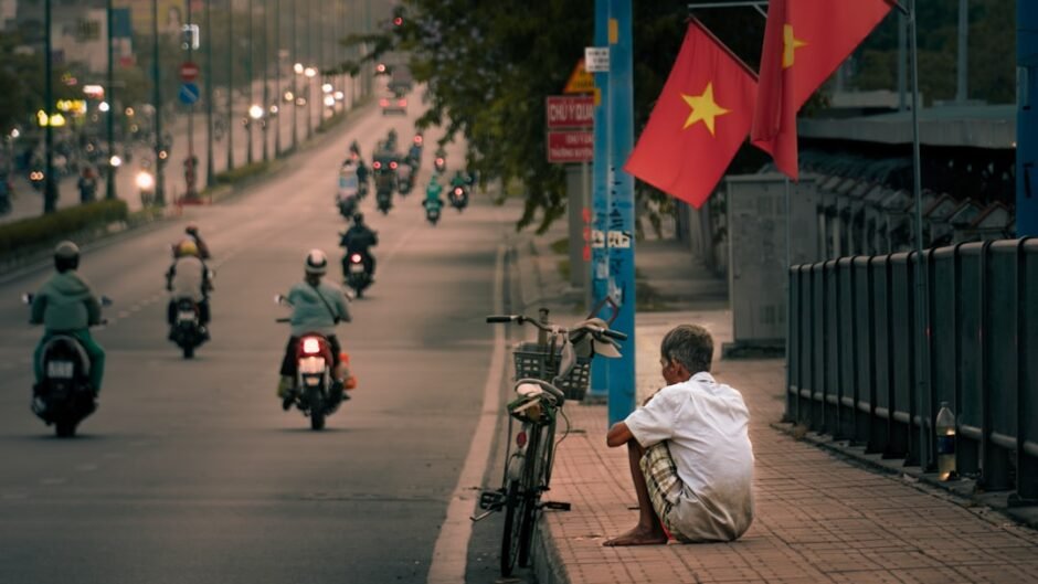 a man sitting on the side of a road next to a motorcycle