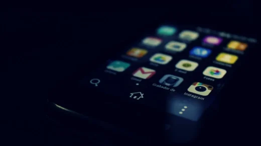 Dark-themed close-up of a smartphone screen highlighting various apps and touchscreen technology.