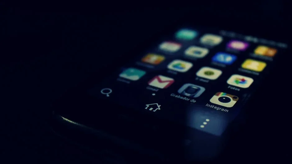Dark-themed close-up of a smartphone screen highlighting various apps and touchscreen technology.