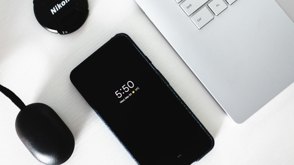 black Android smartphone beside grey laptop computer