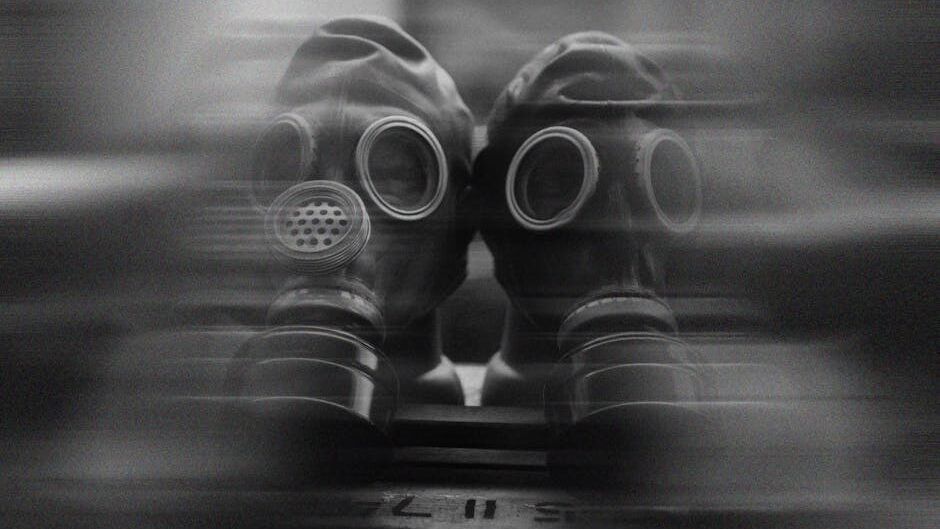 Two gas masks captured in a surreal, blurred black and white image.