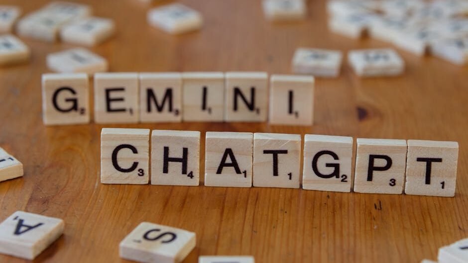 Close-up of wooden Scrabble tiles spelling Gemini and ChatGPT on a wooden surface.