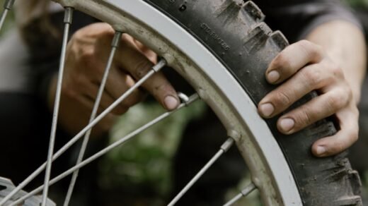 Mechanic using hands to repair a bicycle tire in an outdoor setting.
