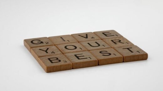 Wooden scrabble tiles arranged to spell 'Give Your Best' on a simple background.
