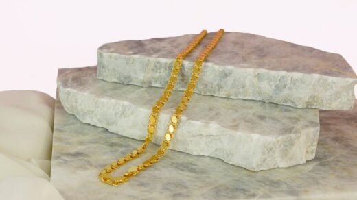 Close-up of a gold necklace elegantly displayed on marble stones, perfect for showcasing luxury jewelry.