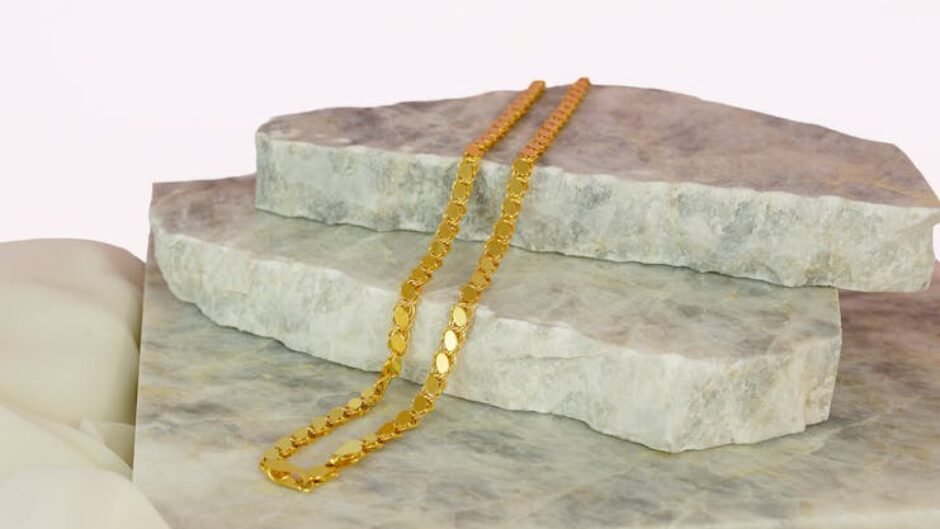 Close-up of a gold necklace elegantly displayed on marble stones, perfect for showcasing luxury jewelry.