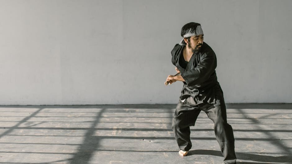 Martial artist in black gi training indoors, showcasing skilled discipline.