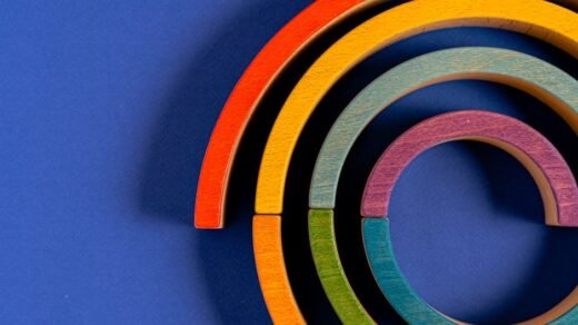 Vibrant wooden rainbow toy pieces arranged against a blue backdrop.