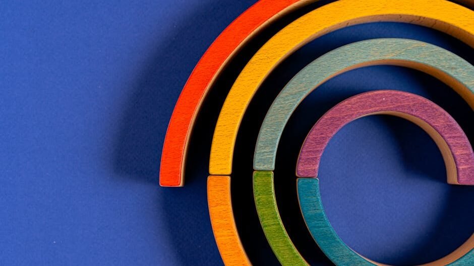Vibrant wooden rainbow toy pieces arranged against a blue backdrop.