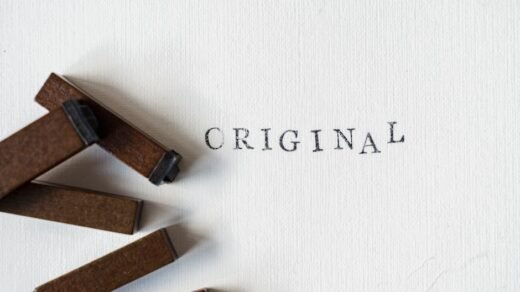 Wooden stamps spelling 'ORIGINAL' on textured paper, minimalistic design.