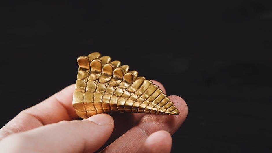 A detailed view of a hand holding an ornate golden dragon scale piece on a black background.