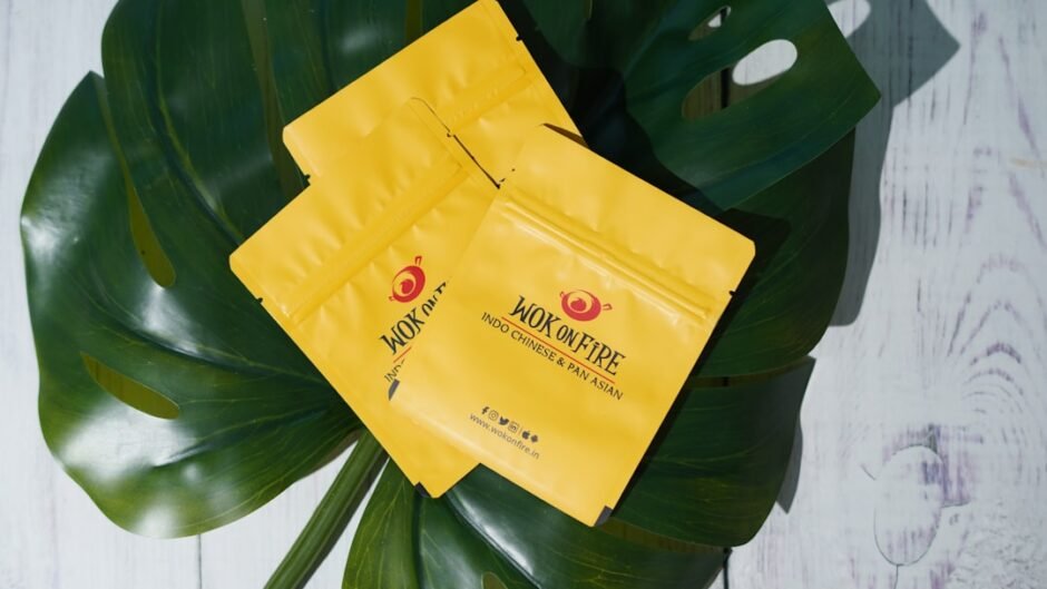 a couple of bags of yellow tea sitting on top of a green leaf