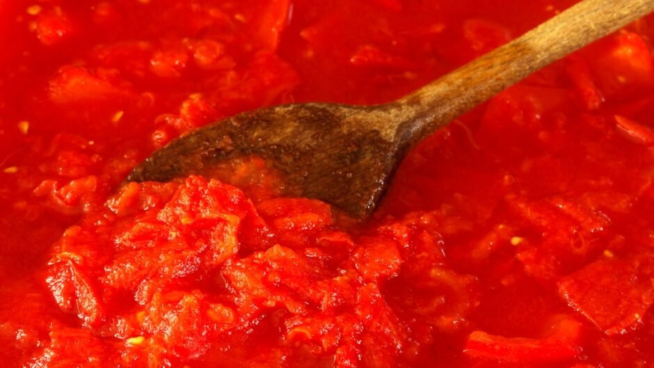 Tomato sauce being stirred with a wooden spoon.